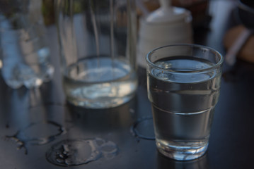 Cold water in a glass on a wooden black table.