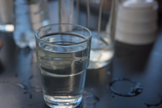 Cold water in a glass on a wooden black table.