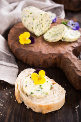 Obraz na płótnie Canvas Sandwich with herb and edible flowers butter on wooden background, healthy food.
