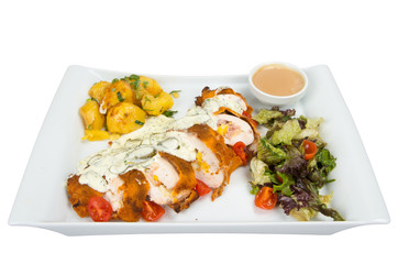 Breaded roll of chicken with zucchini topped with sauce, garnished with lettuce and tomatoes.
