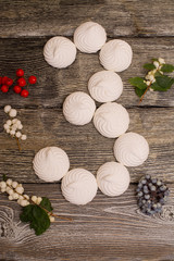marshmallows with berries on wooden table. number 3