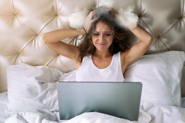 Young woman looking in laptop's screen and holding her steamed head