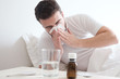 Man feeling cold, lying in the bed and blowing his nose