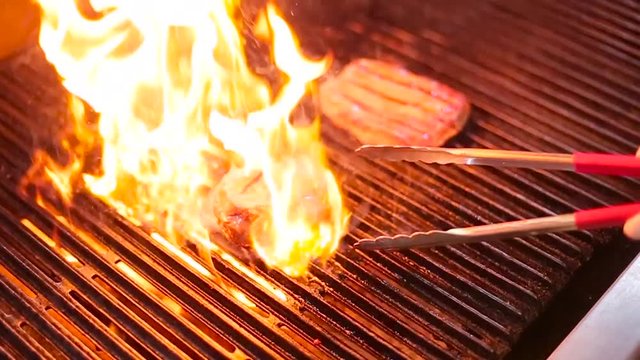 cook frying the meat on the grill.