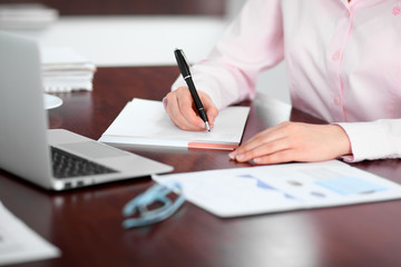 Closeup of a business woman writing in a notebook