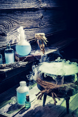 Obraz premium Mysterious witcher cauldron with blue smoke and potions for Halloween