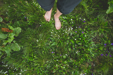 Obraz premium Female standing barefoot on green grass and flowers