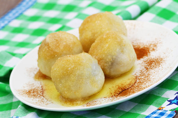 Fruit dumplings sprinkled with sugar and cinnamon on white plate, closeup
