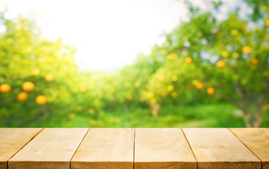 .Wood table top with blur of orange garden farm.