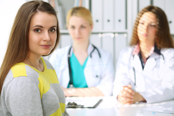 Fototapeta premium Happy female patient with two cheerful doctors in the background. Medical and health care concept