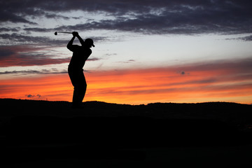 Golfer playing golf during sunset at competition event