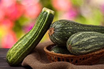 green zucchini on the wooden table with sacking and a blurred background