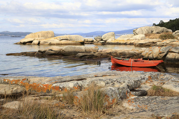 orange fishing boat moored in the rocks