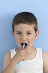 kid brushing his teeth with a toothbrush in a blue background 
