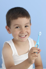 happy child showing his toothbrush in a blue background