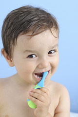 happy baby brushing his teeth  with a toothbrush in a blue background
