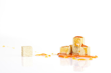 honey on a piece of sugar-coated with gold on a white background