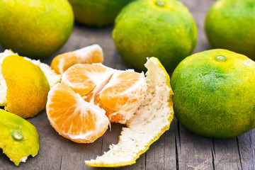 Fresh green peeled tangerine on grey rustic wooden background