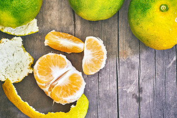 Fresh green peeled tangerine on grey rustic wooden background. Top view with copy space