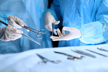 Medical team performing operation. Group of surgeon is working in operating theatre toned in blue - obrazy, fototapety, plakaty