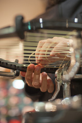 Stringing Machine. Close up of tennis stringer hands doing racket stringing in his workshop