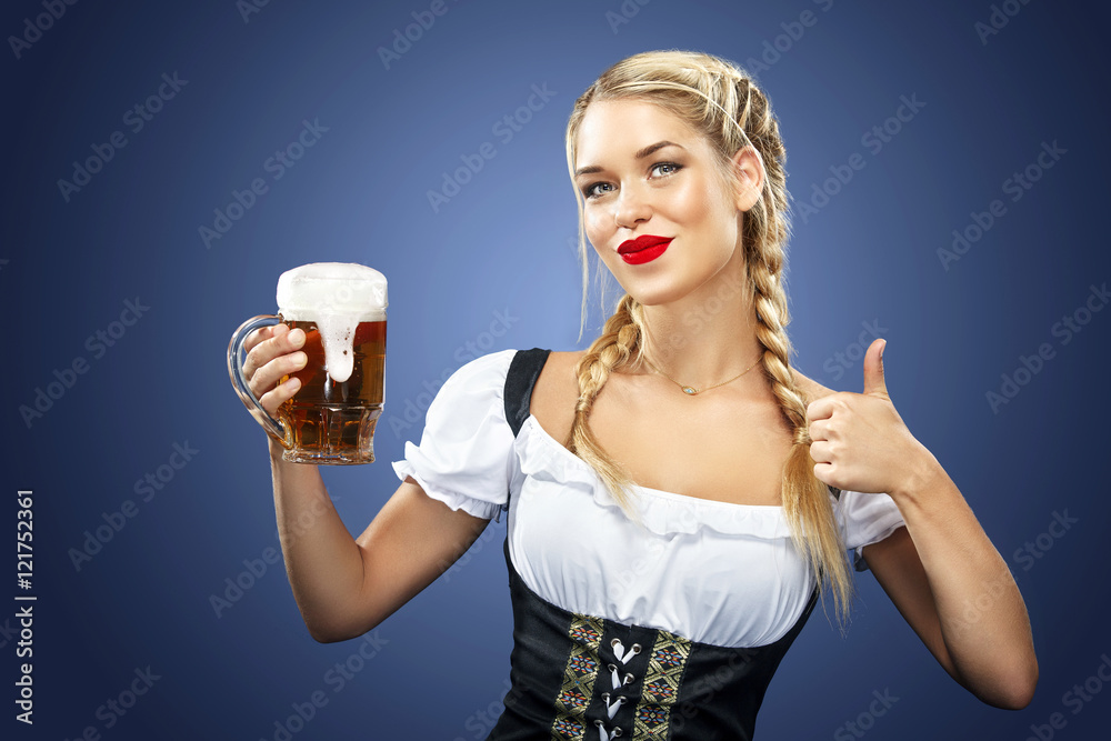 Wall mural Young sexy Oktoberfest waitress, wearing a traditional Bavarian dress, serving big beer mugs on blue background.