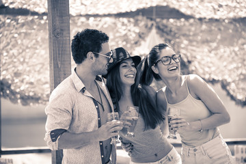 Group of young friends dancing in the beach cafe, relaxing and drinking beer.Beach party.