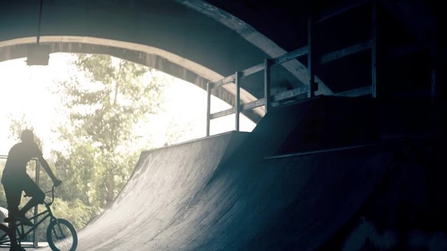 BMX cyclist bicycle riding HD slow motion video. Bike rider in park ramp. Urban teens extreme sport concept