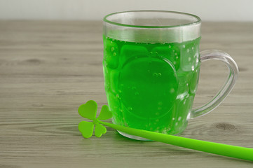 Green liquid in a beer mug displayed with a four leaf clover 