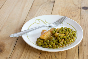 Cooked peas with potatoes on the retro old wooden table