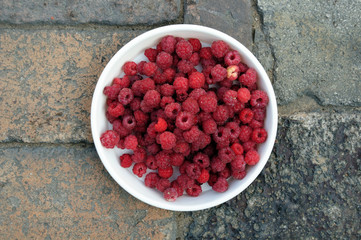ripe juicy red raspberries on a white plate