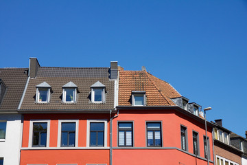 Beautiful red house with dormer windows against a blue sky in summer, some shutters down