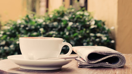 A cup of coffee on the table with newspaper