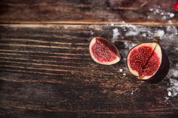 Whole figs and one fig sliced in half on top of a teak garden ta