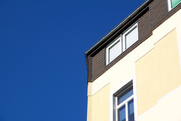 Fototapeta na wymiar Corner of yellow house against a blue sky in Aachen, Germany