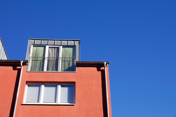 Facade of a red house with dormer windows against a blue sky in Aachen, Germany
