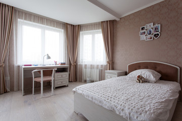 Interior of a bedroomwith a large bed in light brown tones for little girl