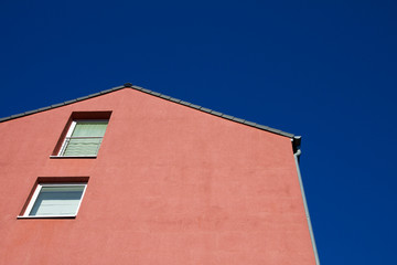 House with a red facade against a blue sky in Aachen, Germany