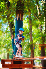 young boy passing the cable route high among trees, extreme sport in adventure park