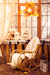 rocking-chair in the room with wooden walls, wicker wreath in autumn style hanging on the window