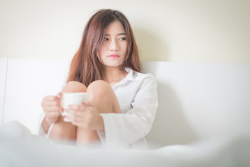 Fototapeta na wymiar Beautiful brunette woman drinking and morning coffee in bedroom