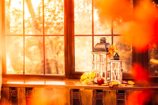 Autumn background. Retro lantern, yellow autumn leaves on windowsill. View through yellow leaves.