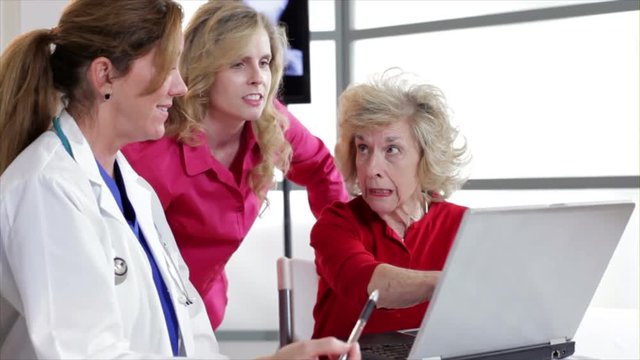 Using a laptop computer a pretty physician discusses test results with an elderly patient and her daughter.