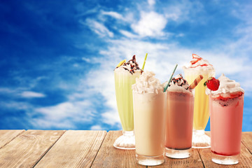 Delicious milkshakes on blue sky background