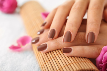 Female hands with brown manicure on wicker bamboo mat