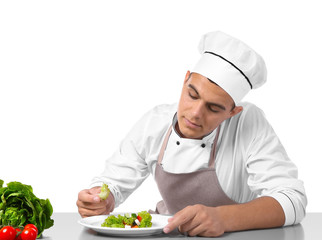 Young handsome chef cook making salad isolated on white