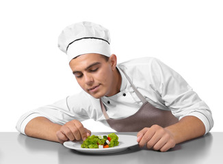 Young handsome chef cook making salad isolated on white
