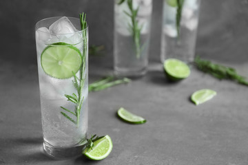 Glass of cocktail with ice on grey background
