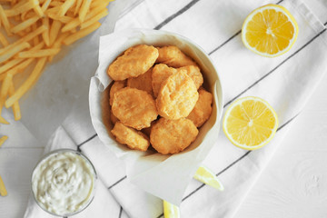 Tasty nuggets in plate and lemon on napkin