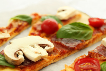 Sliced tasty pizza on parchment, closeup